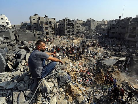 A man sits on the rubble as others wander among debris of buildings that were targeted by Israeli airstrikes in Jabaliya refugee camp, northern Gaza Strip on November 1, 2023.  