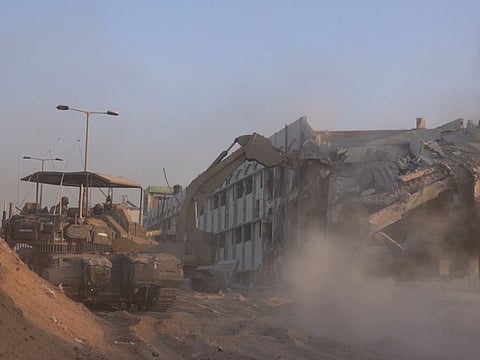 Israeli military bulldozer demolishes a building inside the Gaza Strip, amid the ongoing ground operation of the Israeli army against Palestinian Islamist group Hamas, in this handout picture obtained by Reuters on November 7, 2023.  