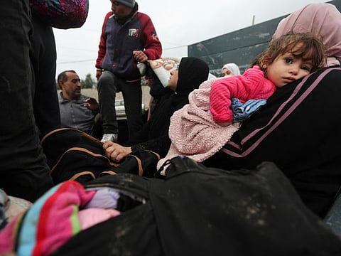 A woman holding a girl sits in a trailer as Palestinians fleeing north Gaza move southward during a temporary truce between Israel and Hamas, near Gaza City, on November 27, 2023.  