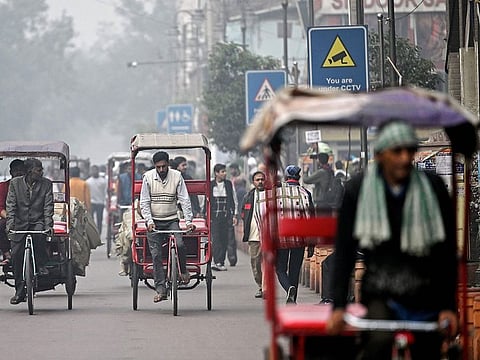 Rizwan (C) pedals a tricycle rickshaw as he looks for customers amid dense smog, along a street in the old quarters of New Delhi.
