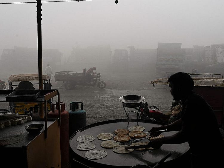A man makes bread along a road amid heavy smog in Lahore 