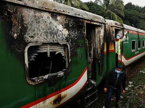 Crime Scene Unit members inspect the passenger train that was set on fire during a countrywide strike called by the Bangladesh Nationalist Party, ahead of the general election, in Dhaka, on December 19, 2023. 