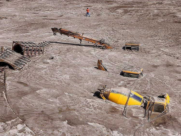 File photo: A man walks past construction vehicles covered in debris