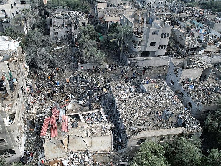 Palestinians gather at the site of Israeli strikes on houses, at the Maghazi camp in the central Gaza Strip, December 25, 2023. 