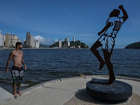 A man look at a statue depicting Brazilian football legend Pele, design by Brazilian artist Luis Costa, at Rei Pele pier, in Sao Vicente, coast of Sao Paulo state, Brazil, on December 19.