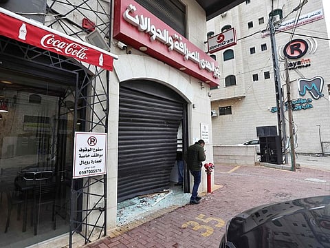 A Palestinian man inspects the damage to a money exchange shop, after a raid by the Israeli army, in the city of Ramallah in the occupied West Bank on December 28, 2023.