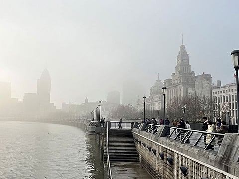 People stand on the Bund as buildings along the Huangpu river are seen shrouded in fog, amid a red alert for heavy fog in Shanghai, China December 29, 2023. The severe weather was due to high humidity and poor atmospheric diffusion conditions, the forecaster said. 