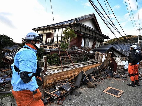 Firefighters inspect collapsed wooden houses in Wajima, Ishikawa prefecture.