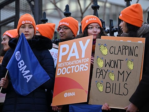 Junior doctors hold placards calling for better pay as they stand on a picket line outside St Thomas' Hospital in central London on January 3, 2024.