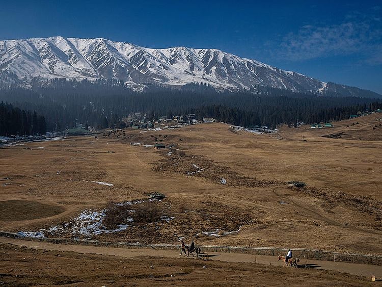  Tourists take a horse ride on grassy, snowless ski slopes in Gulmarg, northwest of Srinagar, on January 13, 2024. There is hardly any snow at Asia’s largest ski terrain in Gulmarg where thousands of domestic and international tourists would usually visit to ski and sledge its stunning snowscape in winter. 