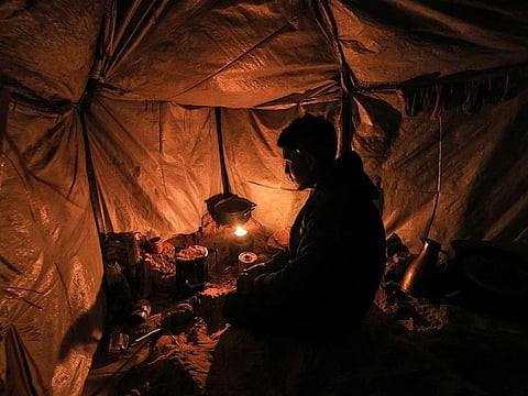 A displaced Palestinian bakes flatbread on a makeshift stove inside his tent at a camp west of Rafah near the Egyptian border.