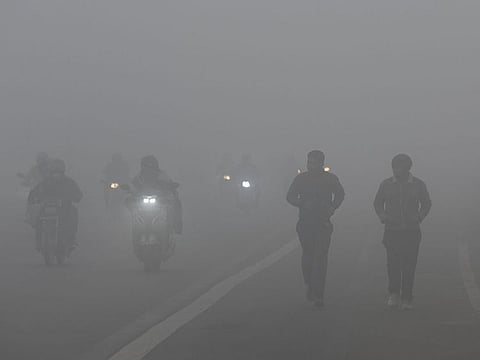 Commuters move through the dense fog on a cold winter morning in India.