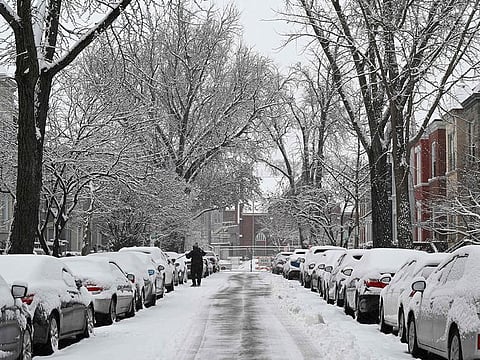 A man clears snow from his car in a Washington, DC, neighbourhood on January 19, 2024.  