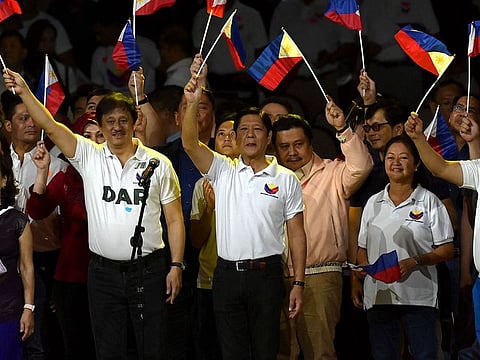 Philippine President Ferdinand Marcos Jr (C) waves the national flag during the kick-off rally for the New Philippines movement at Quirino Grandstand in Manila
