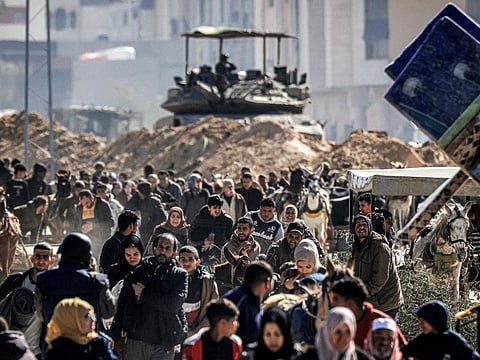 An Israeli battle tank is deployed to guard a position as displaced Palestinians flee from Khan Younis in the southern Gaza Strip on January 30, 2024.