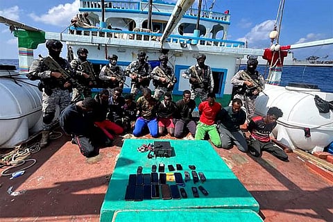 This handout photograph taken on January 30, 2024 and released by the Indian Navy shows commandos stand guard with a group of detained pirates.