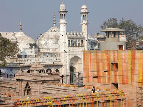 A worker stands on a temple rooftop adjacent to the Gyanvapi Mosque  in the northern city of Varanasi.