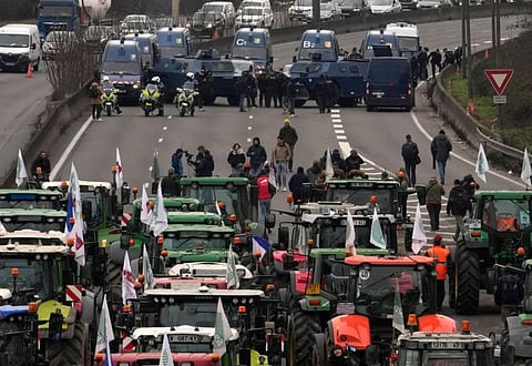 Tractors face military vehicles on a blocked highway, on January 31, 2024 in Chilly-Mazarin, south of Paris.  