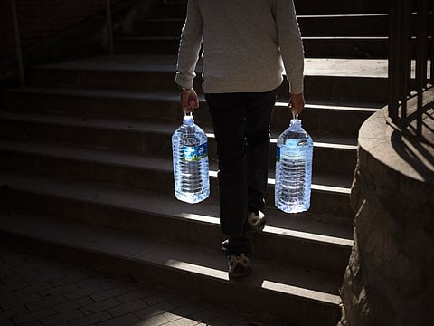 Joan Torrent, 64, walks toward his house carrying two plastic jugs of water refilled at a natural spring in Gualba, about 50km, (31 miles) northwest of Barcelona, Spain, Wednesday, Jan 31, 2024.  