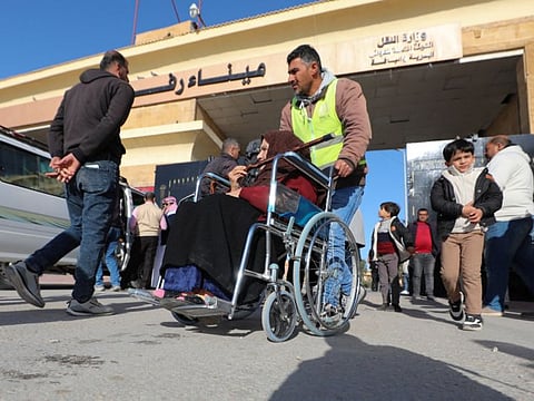A man assists a Palestinian woman in a wheelchair, at the Rafah border crossing between Egypt and the Gaza Strip, amid the ongoing conflict between Israel and Palestinian Islamist group Hamas, in Rafah, Egypt, on February 1, 2024.  