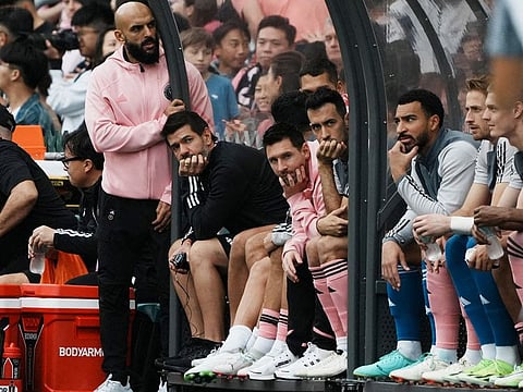 Inter Miami's Lionel Messi, Sergio Busquets and teammates sit on the substitute bench during the match.