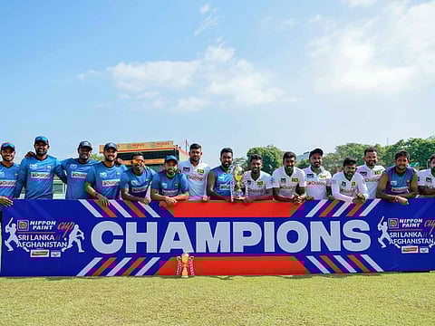 Sri Lankan players pose with the series trophy after their victory at the one-off Test cricket match against Afghanistan at the Sinhalese Sports Club in Colombo on Monday.