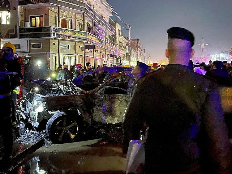 Iraqi federal police gather at the site of a burned vehicle targeted by a US drone strike in east Baghdad, on Wednesday, February 7, 2024. 