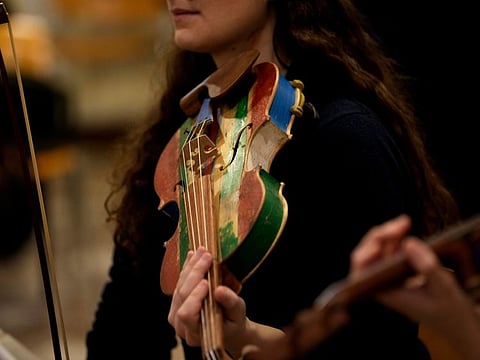 A woman member of the 'Sea Orchestra' rehearses with violin made from the wood of wrecked immigrants' boats in Milan, northern Italy, on February 10, 2024.  