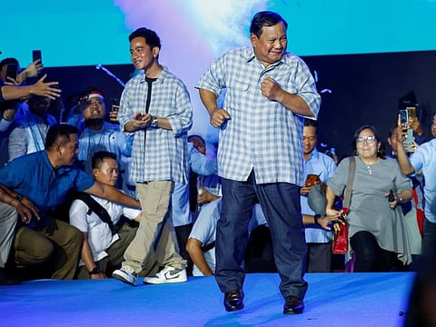 Prabowo Subianto, along with his running mate Gibran Rakabuming Raka, the eldest son of Indonesian President Joko Widodo and current Surakarta's Mayor, dance after delivering their speeches at an event showing the quick-count results of after the general election in Jakarta on February 14, 2024.  