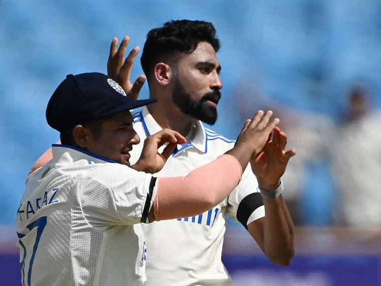 India's Mohammed Siraj (R) celebrates with a teammate after taking the wicket of England's James Anderson during the third day of the third Test cricket match between India and England at the Niranjan Shah Stadium in Rajkot on February 17, 2024.