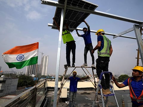 Workers of Solar Square place a panel on the rooftop of a residence in Gurugram on the outskirts of New Delhi.