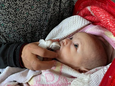 Palestinian woman Warda Mattar feeds her newborn a date wrapped in guaze, instead of milk, amidst food scarcity and lack of milk, at a school where they shelter in Nuseirat in the central Gaza Strip.