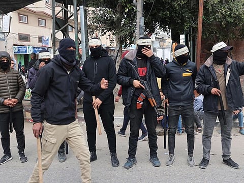 Masked members of the so-called "Popular Committees of Protection", some armed with batons, patrol the streets of Gaza's southern city of Rafah on March 6, 2024.  