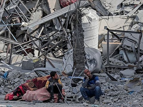 Displaced Palestinians sit with their belongings amid the rubble of houses destroyed by Israeli bombardment in Khan Yunis in Southern Gaza 