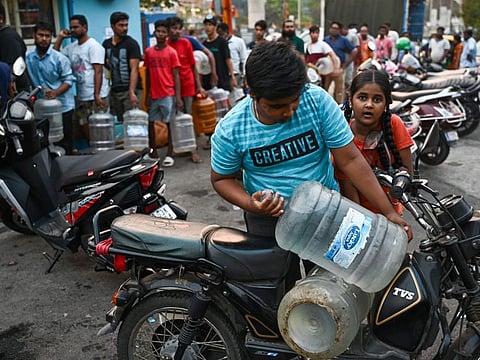 People wait in a queue with cans to collect drinking water amid an ongoing water crisis in Bengaluru.