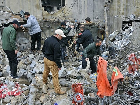 People inspect destruction at the site of an overnight Israeli airstrike in Habariyeh near the Israeli border on March 27, 2024. A Lebanese militant organisation closely linked to Palestinian group Hamas said on March 27 that seven people were killed in an overnight strike in south Lebanon.  