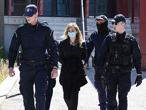 Police officers escort to court Roula Pispirigou (C), a 35-year-old woman prosecuted for having killed her three daughters in three years, in Athens on March 29, 2024.  