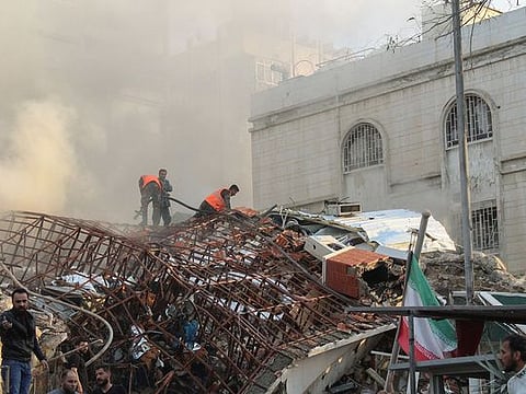 Members of the civil defence stand near a damaged site after what Syrian and Iranian media described as an Israeli air strike on Iran's consulate in the Syrian capital Damascus.