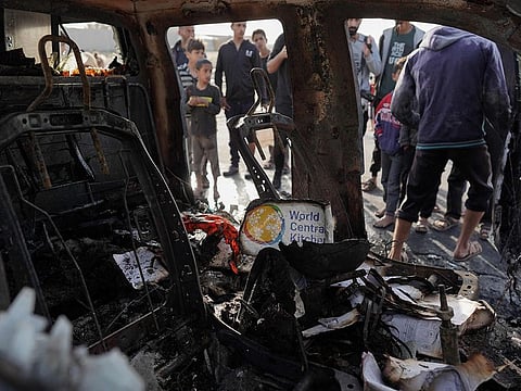 People gather around the carcass of a car used by US-based aid group World Central Kitchen, that was hit by an Israeli strike the previous day in Deir Al Balah in the central Gaza Strip on April 2, 2024.  