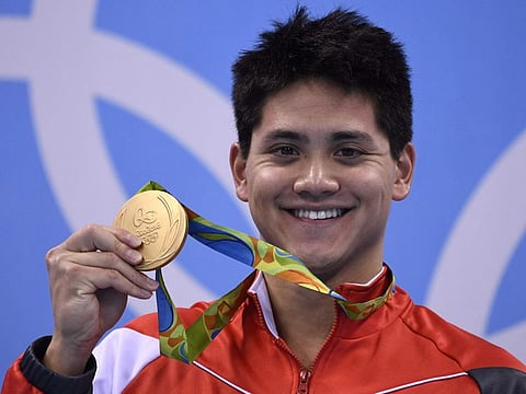 Singapore's Joseph Schooling poses with his gold medal on the podium of the men's 100m butterfly final at the Rio 2016 Olympic Games.