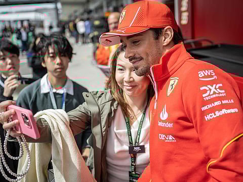 Ferrari's Spanish driver Carlos Sainz Jr takes selfies with a fan in the paddock ahead of the Formula One Japanese GP on Thursday.