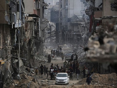 Palestinians walk past damaged buildings in Khan Yunis on April 8, 2024 after Israel pulled its ground forces out of the southern Gaza Strip, six months into the devastating war sparked by the October 7 attacks.  
