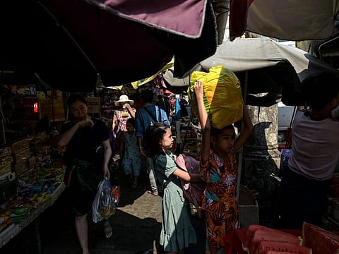 People walk under the shadow at a street market during a heatwave in Yangon on April 2, 2024.  