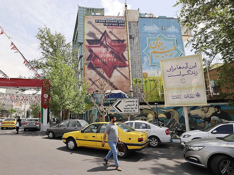 Iranians walk next to an anti-Israel poster in Tehran on April 13, 2024. 