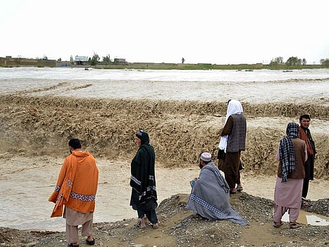 Afghan people wait to cross a flooded area in Spin Boldak district of Kandahar province.