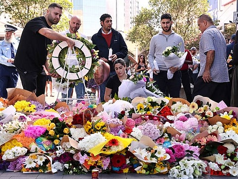 People leave flowers and tributes outside the Westfield Bondi Junction shopping mall in Sydney on April 14, 2024, the day after a 40-year-old knifeman with mental illness roamed the packed shopping centre killing six people and seriously wounding a dozen others. 