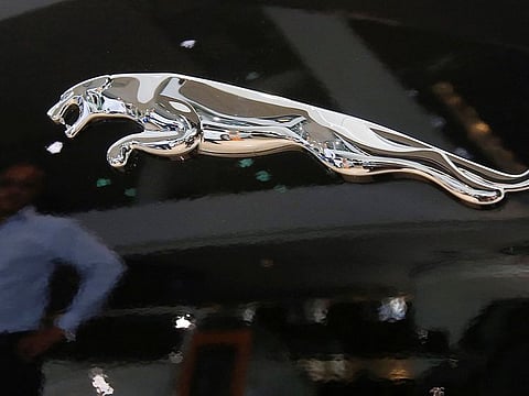 A man is reflected in the logo of a Jaguar vehicle at a Jaguar Land Rover showroom in Mumbai.