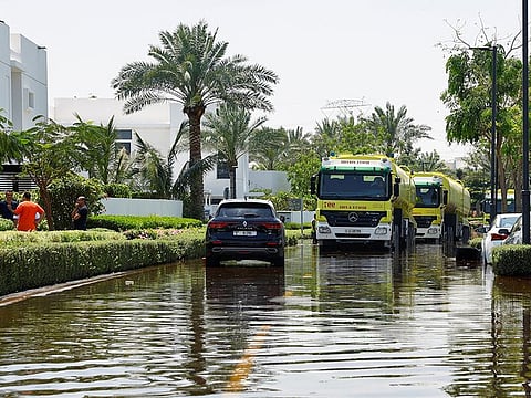 Civil defence trucks drive through a road flooded by heavy rains in a residential community in Dubai.