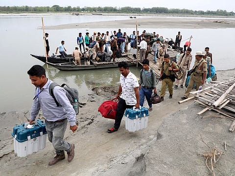 Polling officials carry election materials after disembarking from a boat as they head to a remote polling station ahead of the first phase of India's general election in the Majuli district, in the northeastern state of Assam, on April 18, 2024.  