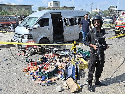 Police officials stand guard at the site of an attack on a vehicle in Karachi on April 19, 2024. 